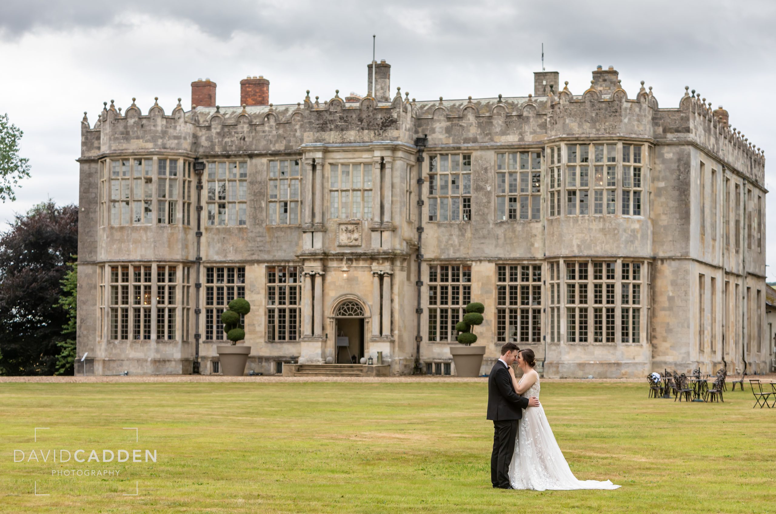 Bride and groom embracing face to face in the grounds of Howsham Hall, Hull, Yorkshire, with the historic hall in the background.