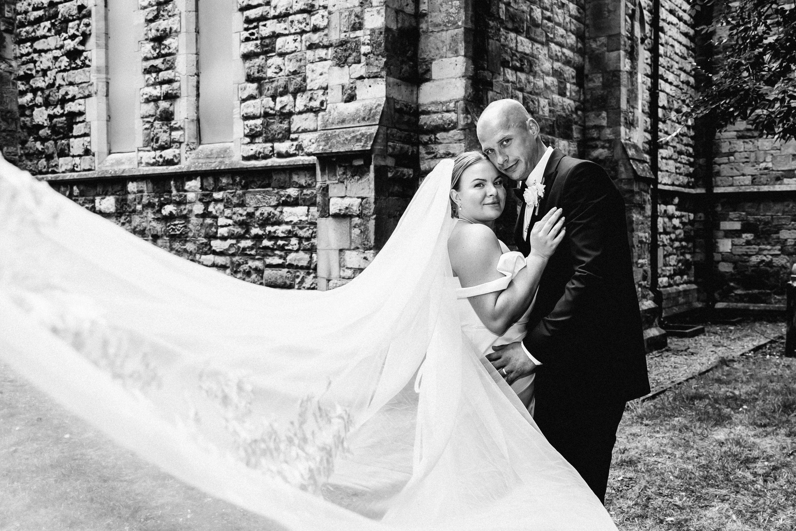 Bride and groom embracing beneath a flowing wedding veil, photographed by David Cadden Photography