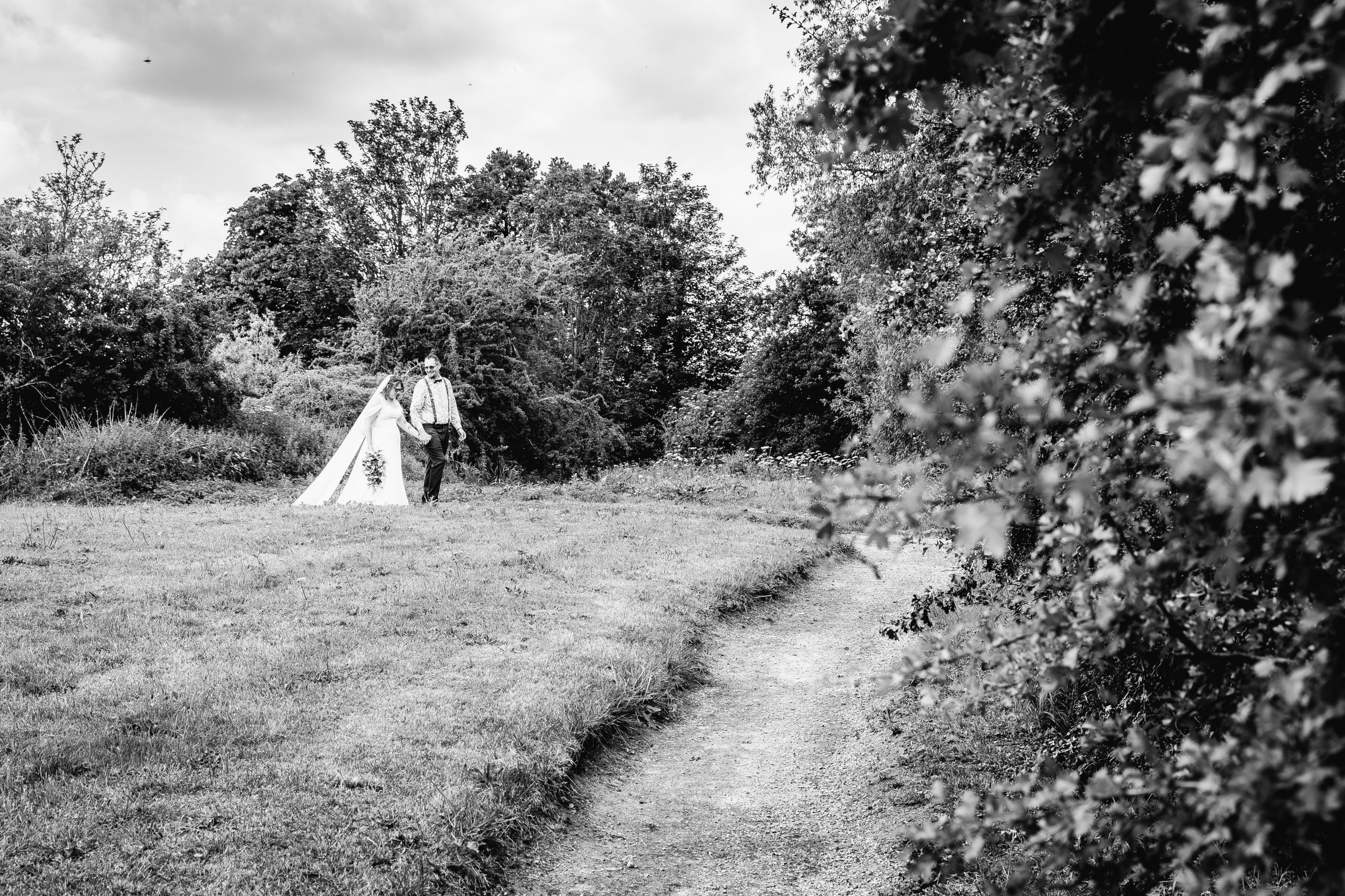 Bride and groom walking together through woodland wedding gardens, photographed by David Cadden Photography
