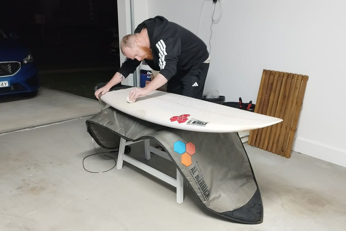 David Cadden waxing his surfboard at home in Port Macquarie before an early morning surf.
